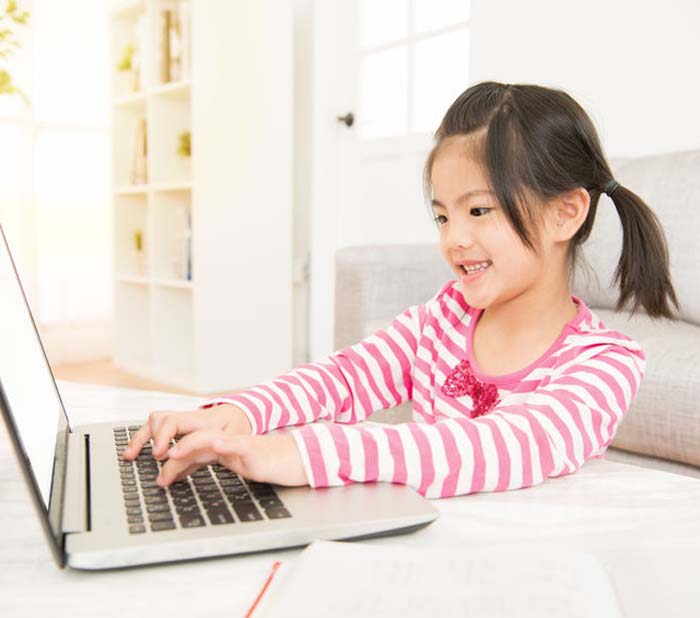 Glad asian schoolgirl with her computer